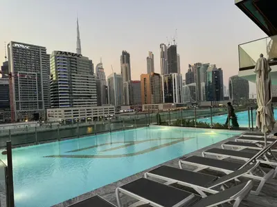 a swimming pool with chairs and a city skyline at Burj Khalifa Poolview 1BR Apartment for 4 people in Dubai