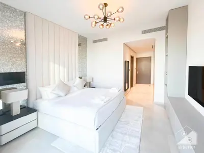 a white bedroom with a large white bed and a television at Luxury Grande Downtown Full Burj khalifa Views in Dubai
