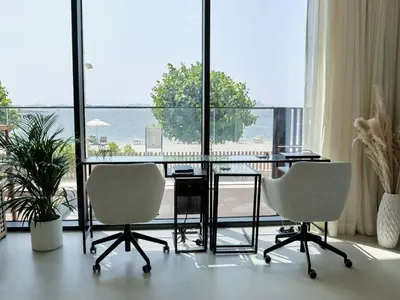 a glass table and two chairs in a room with a large window at Beachfront Townhouse SEA BREEZE in Dubai
