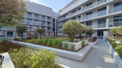 an apartment complex with a courtyard with trees and plants at Deluxe Studio - Stylish & Cosy in Luma22 in Dubai