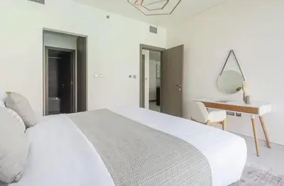 a white bedroom with a white bed and a desk at District one Full Water view Apartment in Dubai