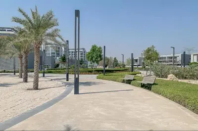 a park with benches and palm trees and a building at District one Full Water view Apartment in Dubai