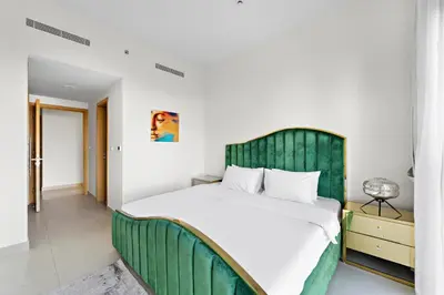 a bedroom with a large bed with a green headboard at 2BR plus Maid Bellevue Tower 1, Burj Khalifa View in Dubai