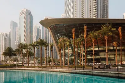 a pool with palm trees in front of a city at 1001 Nights - Luxury 1-BR apartment near Burj in Dubai