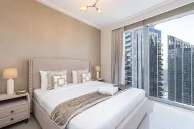 a bedroom with a white bed and a large window at Luxury Apartment in the Heart of Downtown Dubai in Dubai