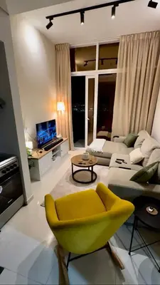 a living room with a yellow chair and a couch at Cozy Golf & Lake View 1BR Apartment,Damac Hills 1 in Dubai