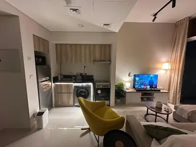 a living room with a couch and a tv in it at Cozy Golf & Lake View 1BR Apartment,Damac Hills 1 in Dubai