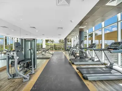 a gym with treadmills and cardio machines at Cozy Golf & Lake View 1BR Apartment,Damac Hills 1 in Dubai