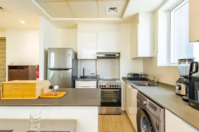 a kitchen with white cabinets and stainless steel appliances at Superhost - Bright & Stylish 1-Bedroom in Bloom Tower, JVC in Dubai