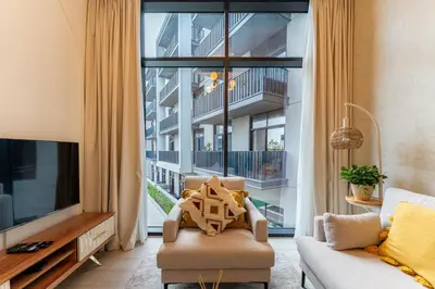 a living room with a tv and a large window at HAVN - 1 Bedroom in Harrington House, JVC in Dubai