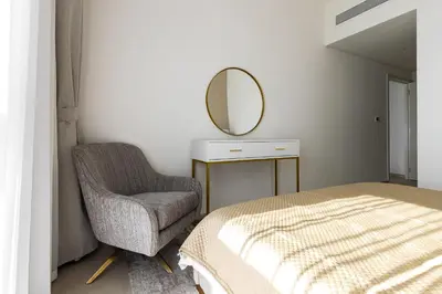 a bedroom with a bed and a chair and a mirror at downtown views 1108 burj in Dubai