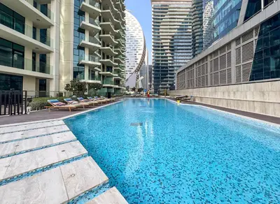 a large swimming pool in a city with tall buildings at Modern 2BR Canal-Side Elegance in Dubai