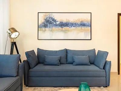 a blue couch in a living room with a painting on the wall at Royal Vista - Luxury 3BR Apartment at 29 Boulevard Tower - Downtown in Dubai