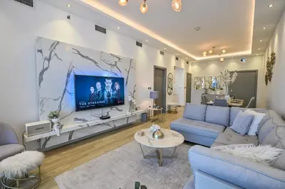 a living room with a blue couch and a tv at Azure Residences a Beachfront Getaway on Palm Jumeirah in Dubai