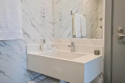 a white bathroom with a sink and a mirror at Azure Residences a Beachfront Getaway on Palm Jumeirah in Dubai
