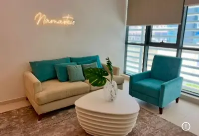 a living room with a couch and two blue chairs at 1 Bedroom by the beach with free Rooftop pool access in Dubai