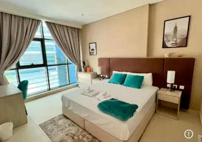 a bedroom with a large bed with blue pillows at 1 Bedroom by the beach with free Rooftop pool access in Dubai