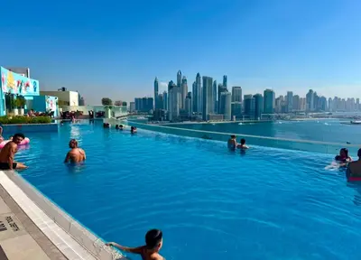 people swimming in a infinity pool with a city skyline at 1 Bedroom by the beach with free Rooftop pool access in Dubai