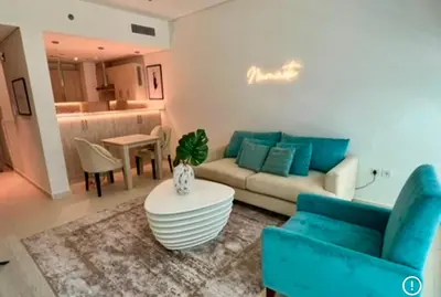 a living room with a blue couch and a table at 1 Bedroom by the beach with free Rooftop pool access in Dubai