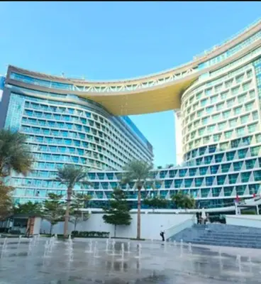 a large building with palm trees in front of it at 1 Bedroom by the beach with free Rooftop pool access in Dubai
