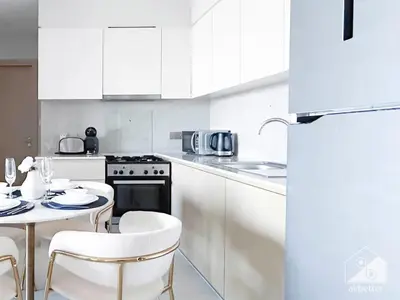 a kitchen with white cabinets and a table and chairs at Burj Royale Luxury One-Bedroom with City Views in Dubai