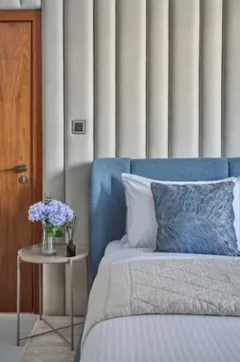 a blue bed with a vase of flowers on a table at Frank Porter - Marina Quays East Tower in Dubai