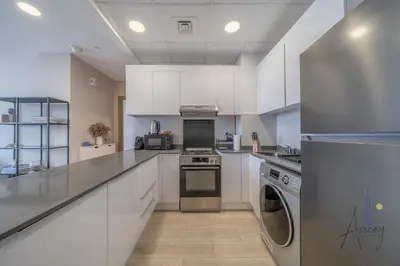a kitchen with white cabinets and stainless steel appliances at Cityview Haven 1BR Modern Flat in Bloom Heights in Dubai
