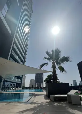 a palm tree in front of a building with a pool at Cityview Haven 1BR Modern Flat in Bloom Heights in Dubai