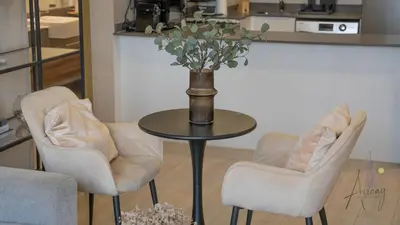 a table with two chairs and a vase with flowers at Cityview Haven 1BR Modern Flat in Bloom Heights in Dubai