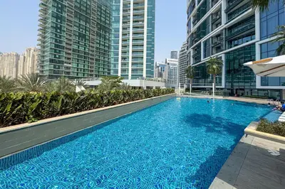 a swimming pool in the middle of a building with tall buildings at Exceptional high floor 3bed apartment by Suiteable in Dubai