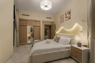 a bedroom with a large white bed and a bathroom at Stunning Waterfront Burj Views with Pool & Gym, Sleeps 6 in Dubai