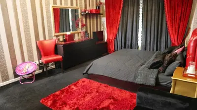 a bedroom with a bed and a red chair at Royal Classic by oima leasing property in Dubai