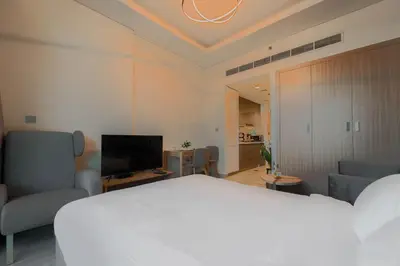 a bedroom with a white bed and a living room at Creek view studio deleguest in Dubai