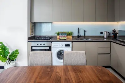 a kitchen with a washing machine and a wooden table at Waves - Spacious 2BR Apartment with Burj Views & Terrace in Dubai