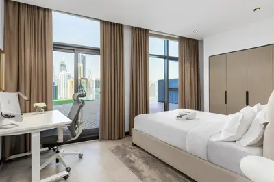 a hotel room with a bed and a desk and a window at Waves - Spacious 2BR Apartment with Burj Views & Terrace in Dubai