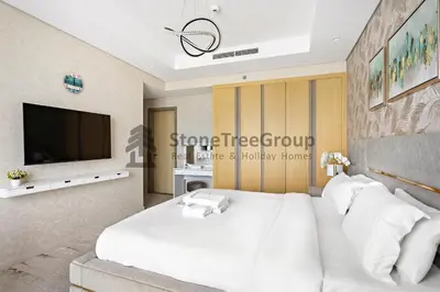 a bedroom with a white bed and a tv at Stonetree - Spacious 2BR in Paramount in Dubai