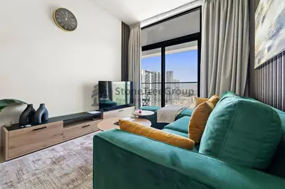 a living room with a blue couch and a large window at High-Floor and Spacious 1BR at Binghatti Emerald in Dubai