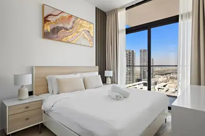 a bedroom with a white bed and a large window at Modern and High Floor 1BR at Binghatti Emerald in Dubai
