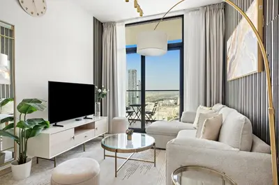 a living room with a tv and a large window at Modern and High Floor 1BR at Binghatti Emerald in Dubai