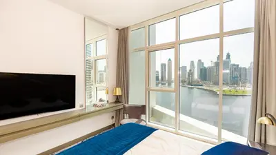 a bedroom with a large tv and a large window at Conveniently Located Apartment With Waterfront View in Dubai
