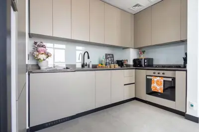 a kitchen with white cabinets and an oven at Luxury Apartment with Burj Khalifa View, Balcony Netflix WeHome Premium in Dubai