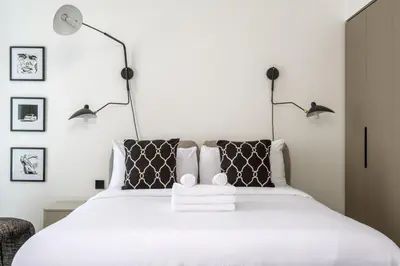 a bedroom with a white bed with two lamps at Studio Revved Up in 15 Northside with Pool and Gym in Dubai