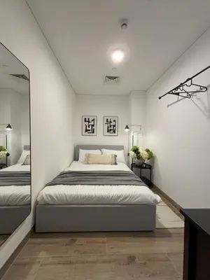 a white bedroom with a bed and a mirror at Oakley Square Oasis in JVC in Dubai