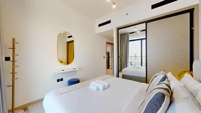 a bedroom with a white bed and a mirror at Locations I Binghatti Luna - JVC I Modern 1BR Apartment I Upgraded Interiors & Comfortable Stay I Scenic Community & Skyline Views in Dubai