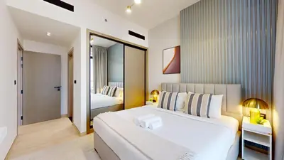 a bedroom with a large white bed and a mirror at Locations I Binghatti Luna - JVC I Modern 1BR Apartment I Upgraded Interiors & Comfortable Stay I Scenic Community & Skyline Views in Dubai