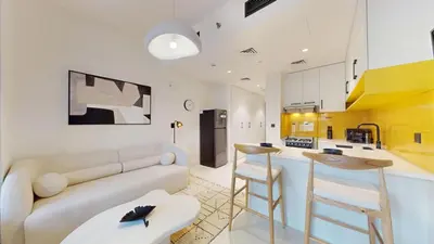 a living room with a couch and a kitchen at Loci Residences - Vibrant Studio in JVC in Dubai