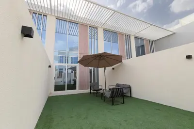 a patio with a table and chairs and an umbrella at Family Friendly, 2BR Townhouse in Rukan Community, Dubai Land - Allsopp & Allsopp in Dubai