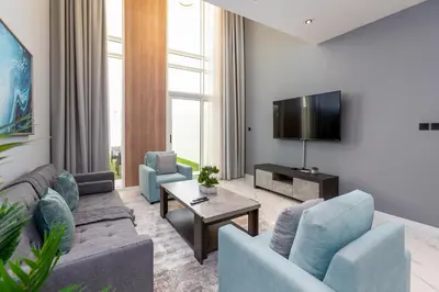 a living room with a couch and a tv at Family Friendly, 2BR Townhouse in Rukan Community, Dubai Land - Allsopp & Allsopp in Dubai
