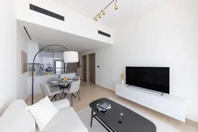 a living room with white furniture and a tv at Bright 1BR with balcony in Binghatti Corner in Dubai