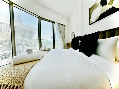 a bedroom with a large white bed with large windows at Venduras Homes -Grande Tower, Downtown Dubai, Burj Khalifa & Fountain Views in Dubai